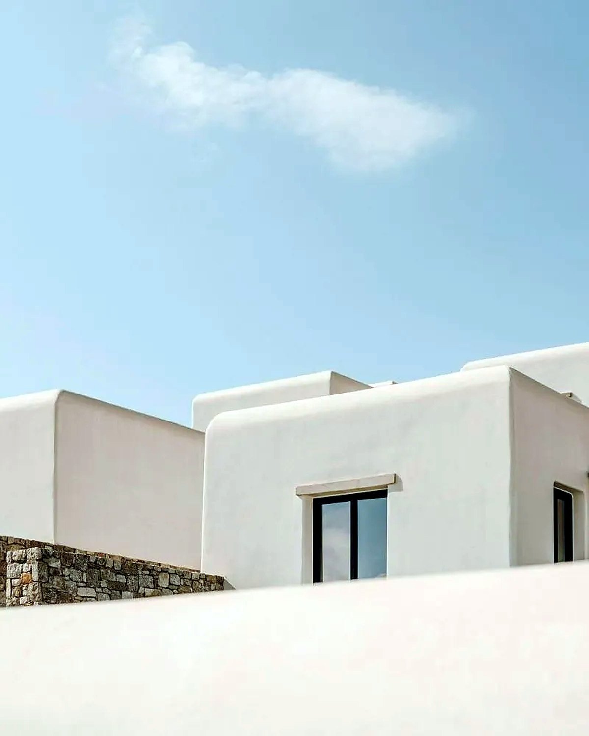 Contemporary white-rendered residence with stone garden wall and black-framed glazing