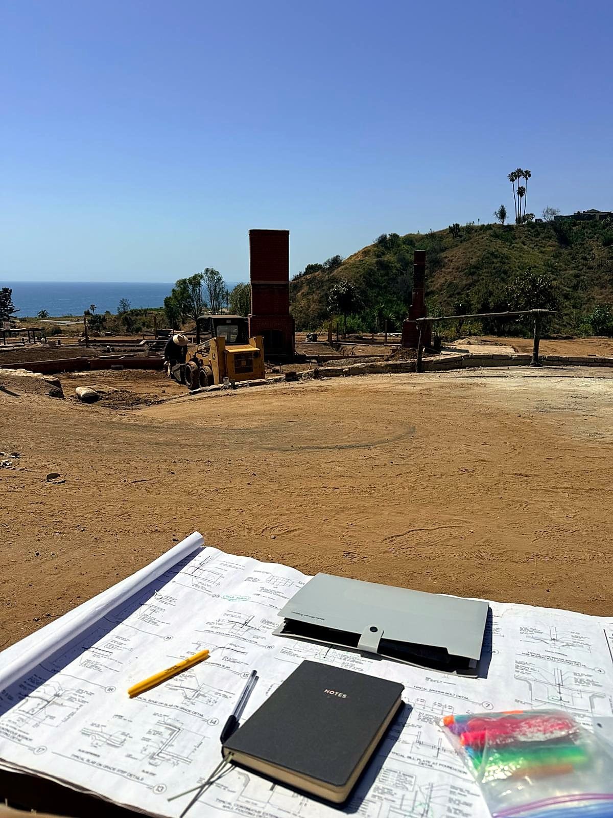 TMA Design structural drawings laid out on site during construction, with the build under way behind